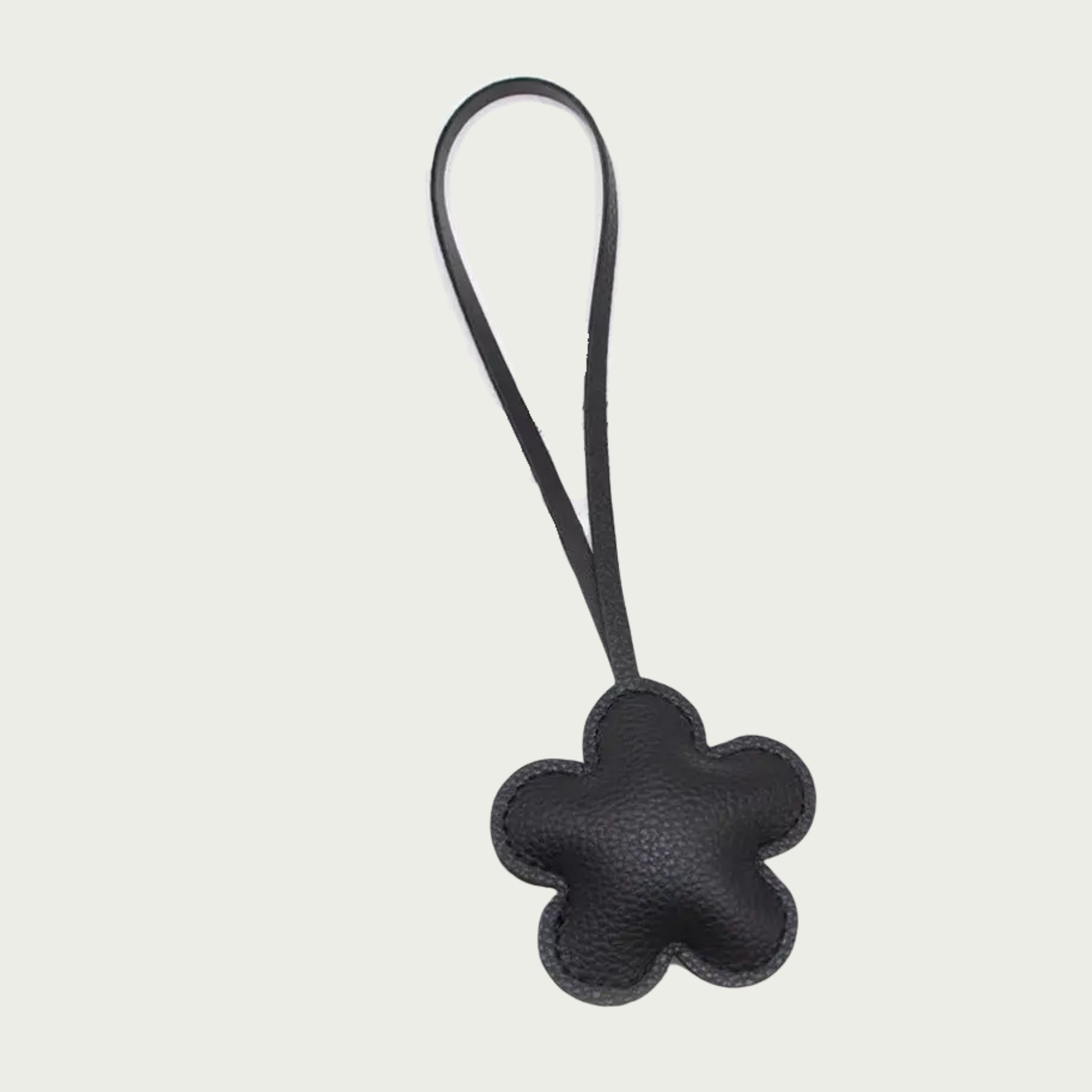 Zoom sur les détails du bijou de sac La Fleur, avec son design floral en cuir noir vegan texturé.