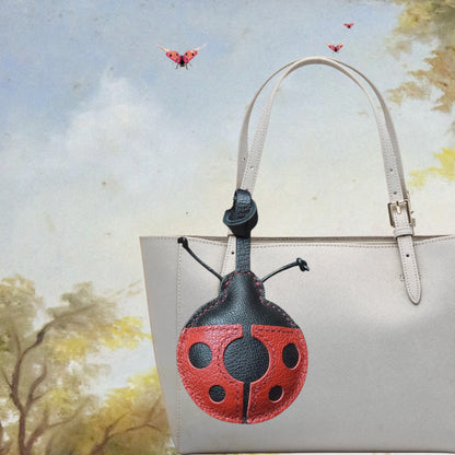 Bijou de sac en cuir en forme de coccinelle rouge et noire, avec finitions cousues et antennes.