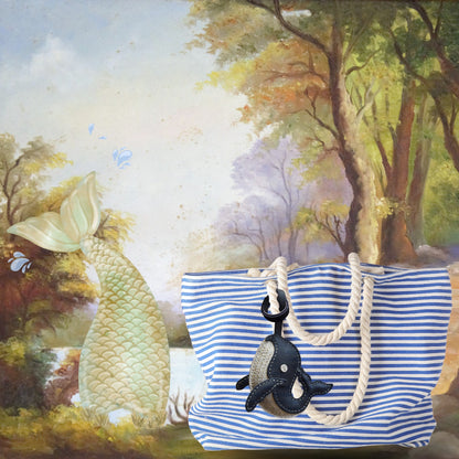 Gracieuse, bijou de sac en cuir noir ou bleu marine attaché à un sac rayé – inspiration bord de mer.