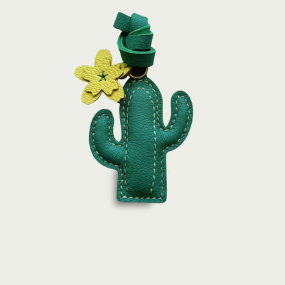 Accessoire de sac en cuir Le Cactus avec une fleur jaune, à suspendre à un sac à dos, avec élégance en pleine nature lors d’un voyage.