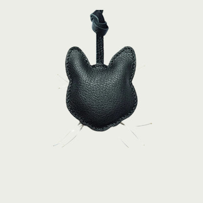 Détail du bijou de sac en cuir grainé avec un lanyard représentant l'arrière de la tête d'un chat noir.