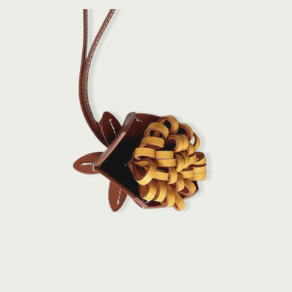 Charm fleur en cuir de vachette, de couleur marron foncé, bijou de sac romantique et raffiné, parfait pour embellir vos accessoires au quotidien.