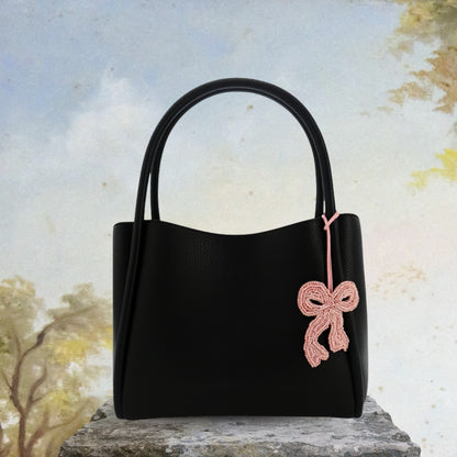 Bijou de sac Darling en perles roses accroché à un sac noir, vue lookbook.