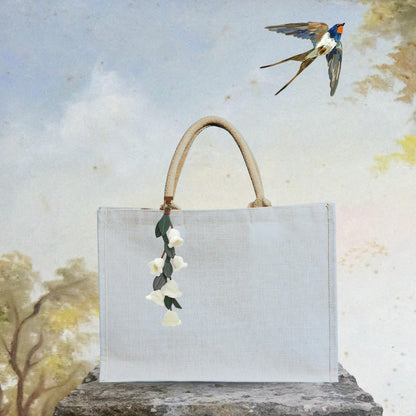 Fleur de muguet accrochée à un sac cabas, bijou de sac Lily of the Valley, style printanier.