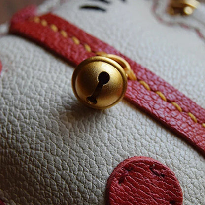 Zoom sur le grelot doré du bijou de sac Maneki-Neko en cuir véritable, cousu main.