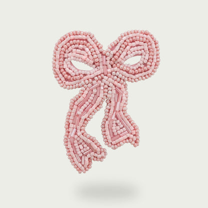 Gros plan sur le bijou Darling en forme de nœud rose bonbon brodé à la main.